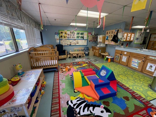 A colorful classroom with cribs, play mats, and learning materials