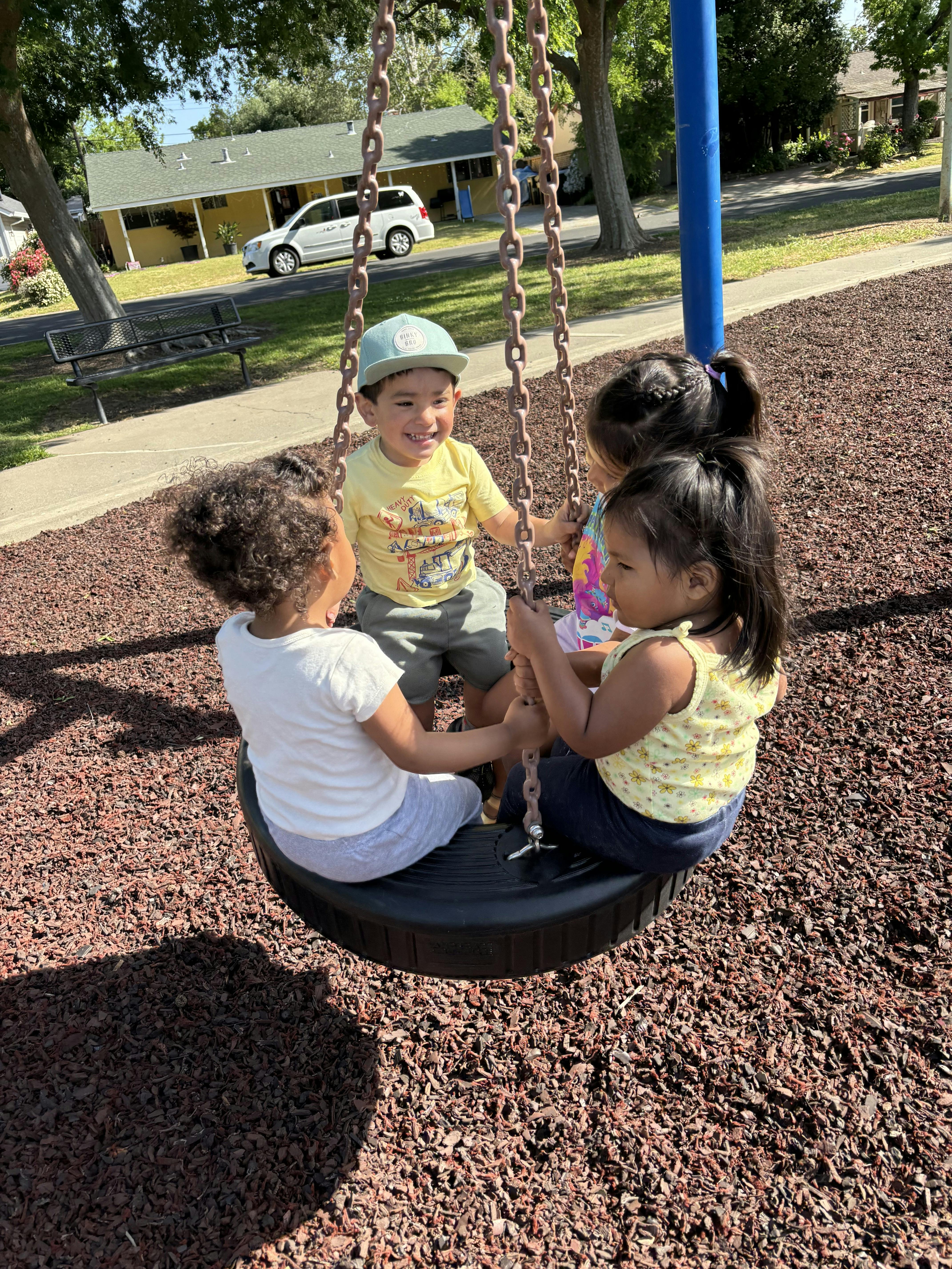 Four children sitting together on a tire swing