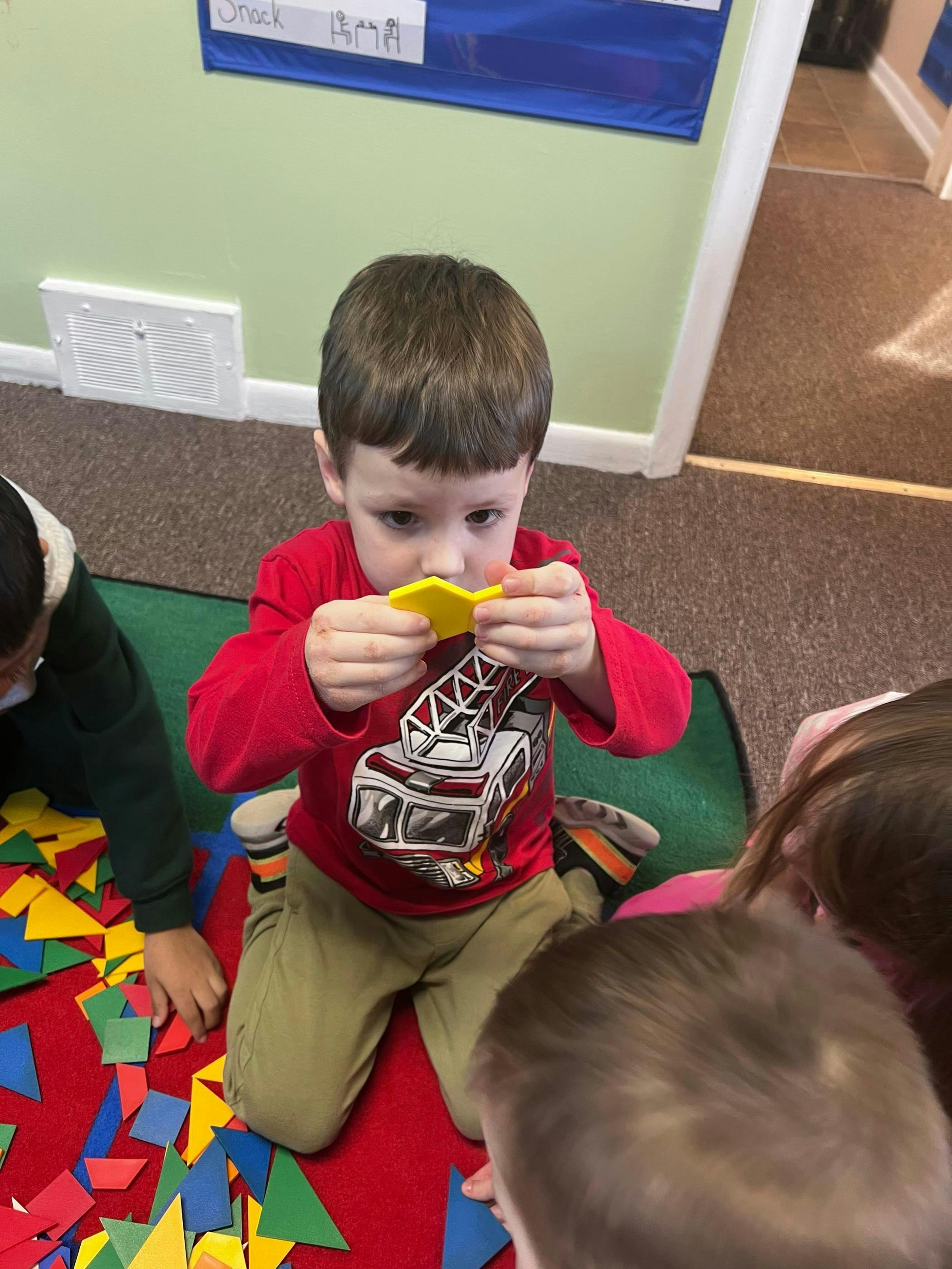 Child in a red shirt playing with yellow shapes