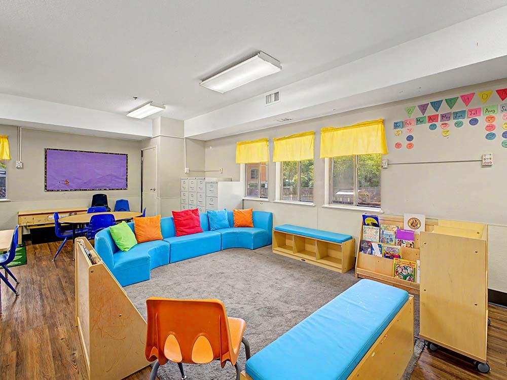 Classroom with blue modular seating, colorful cushions, and small tables