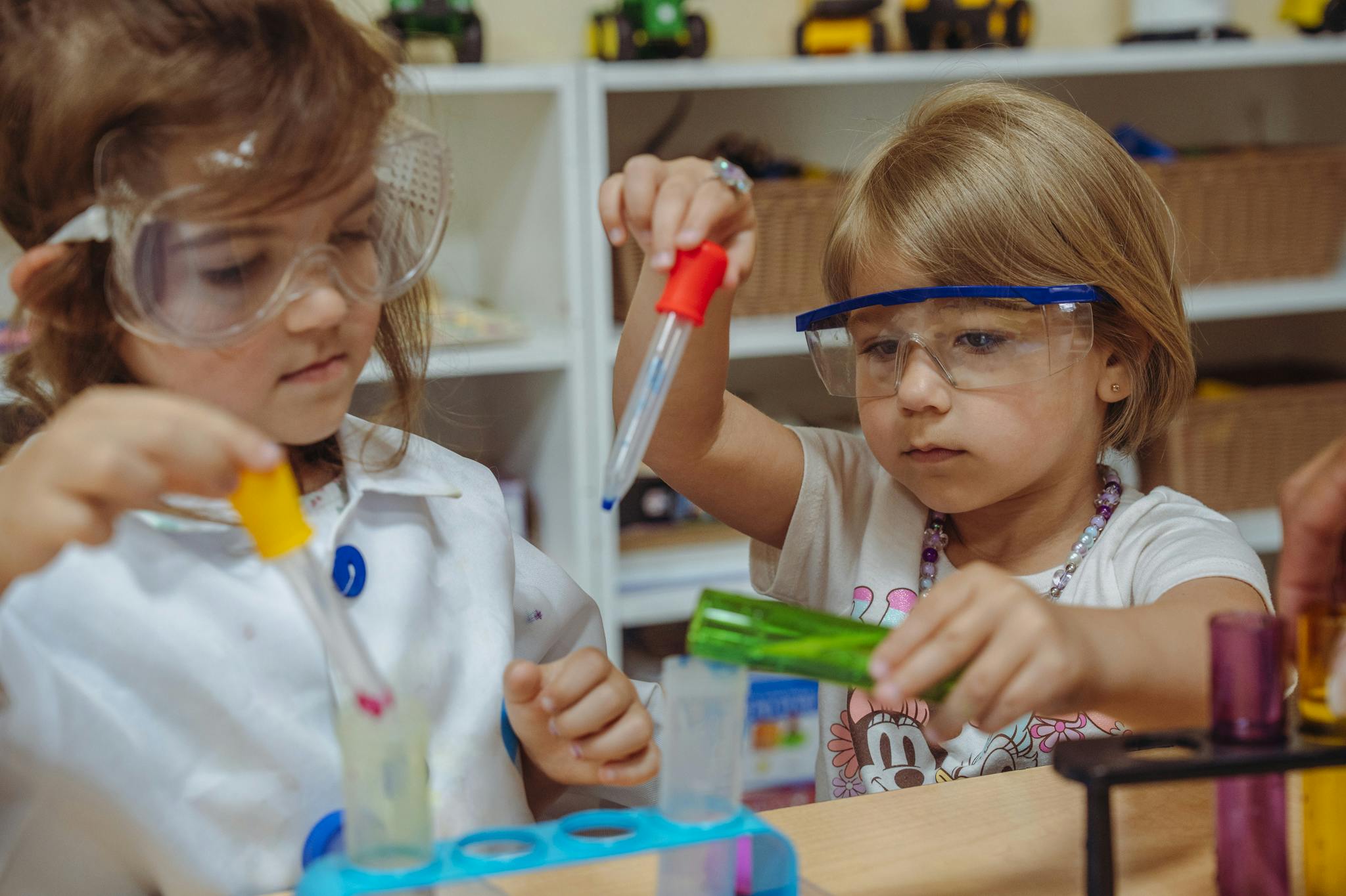 Two children in safety glasses doing a science experiment with test tubes