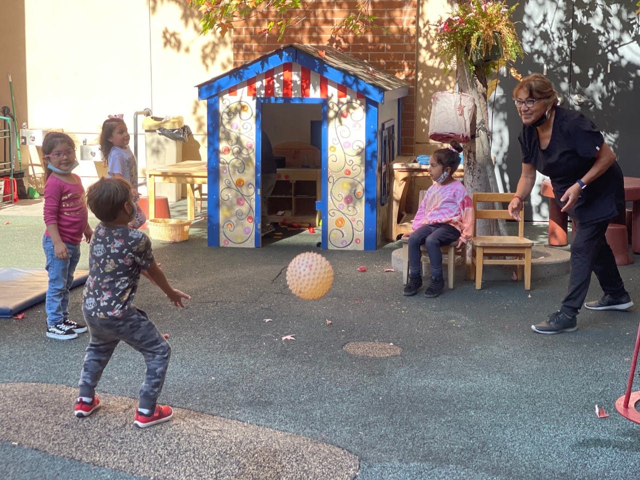 Adult and children playing with a ball outdoors