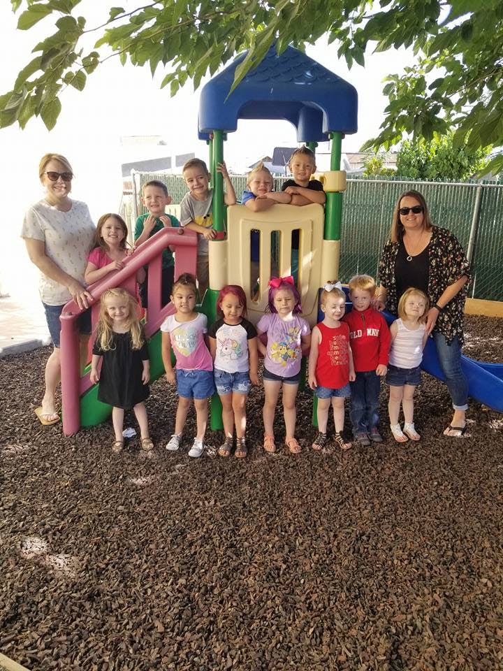 Two adults and multiple children on a playground