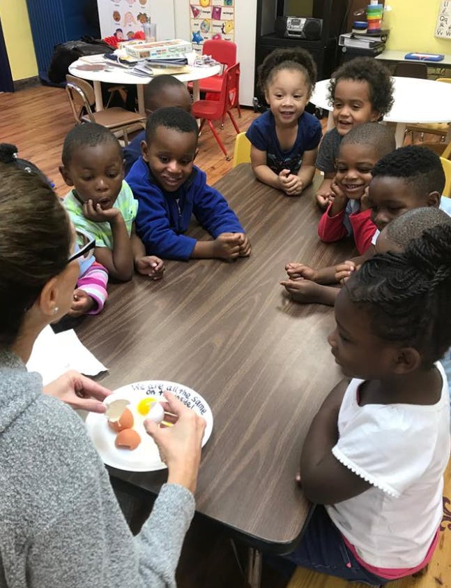 Person showing children a cracked egg on a plate