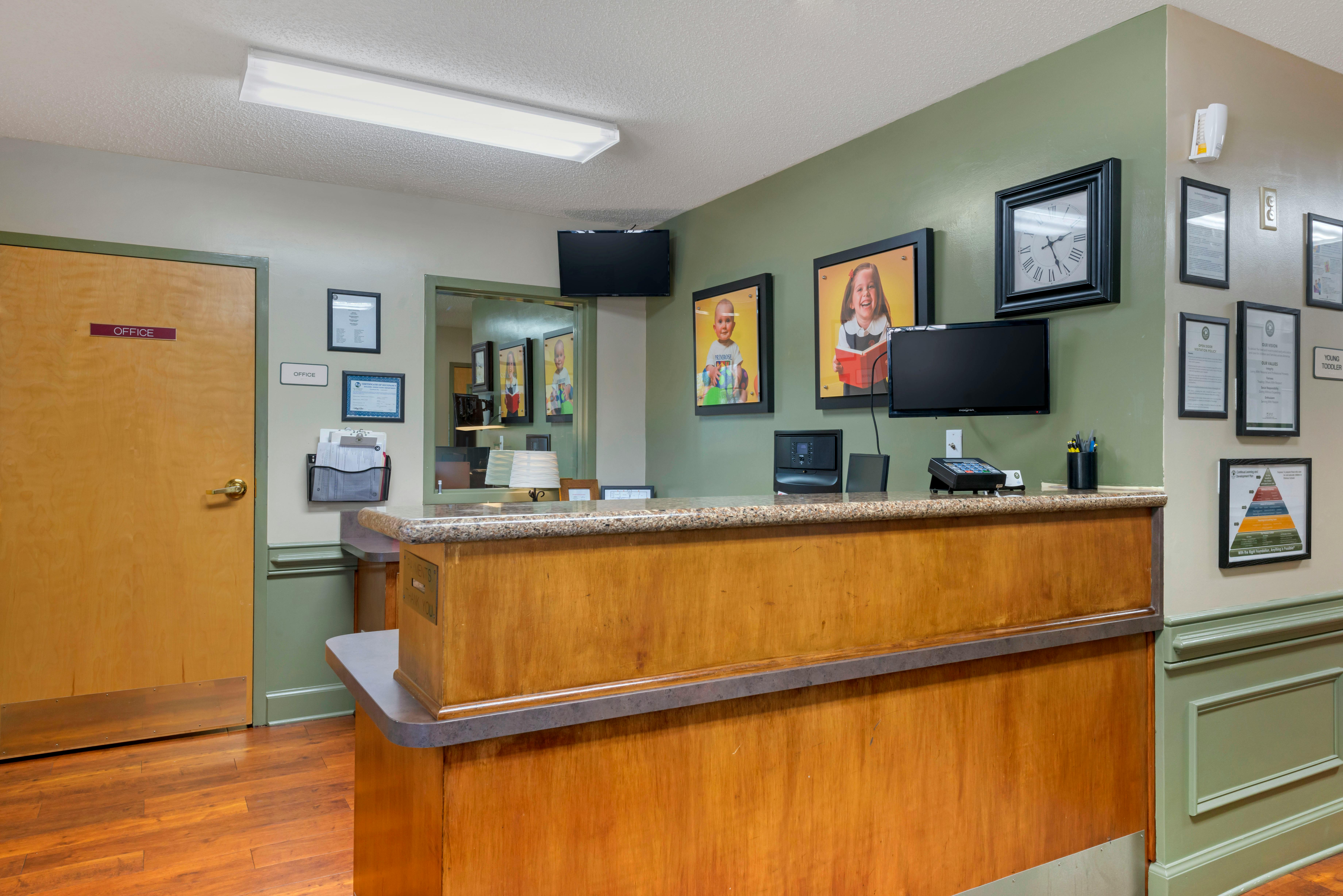 Reception desk with office door, monitors, and framed pictures of children