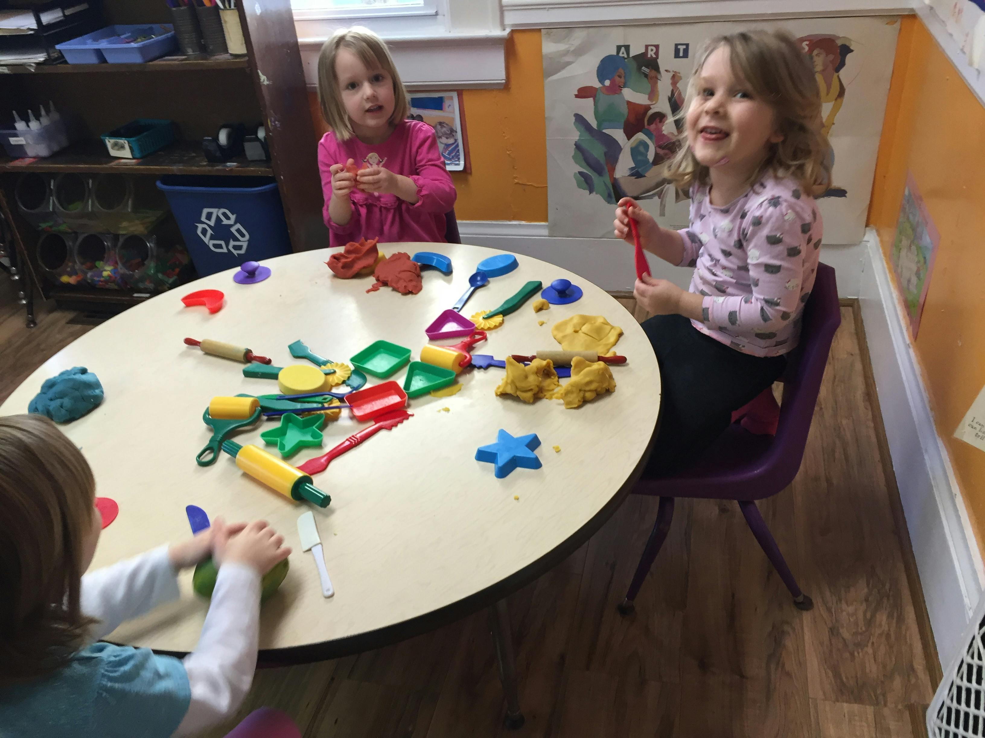 Children playing with modeling clay and tools at a table