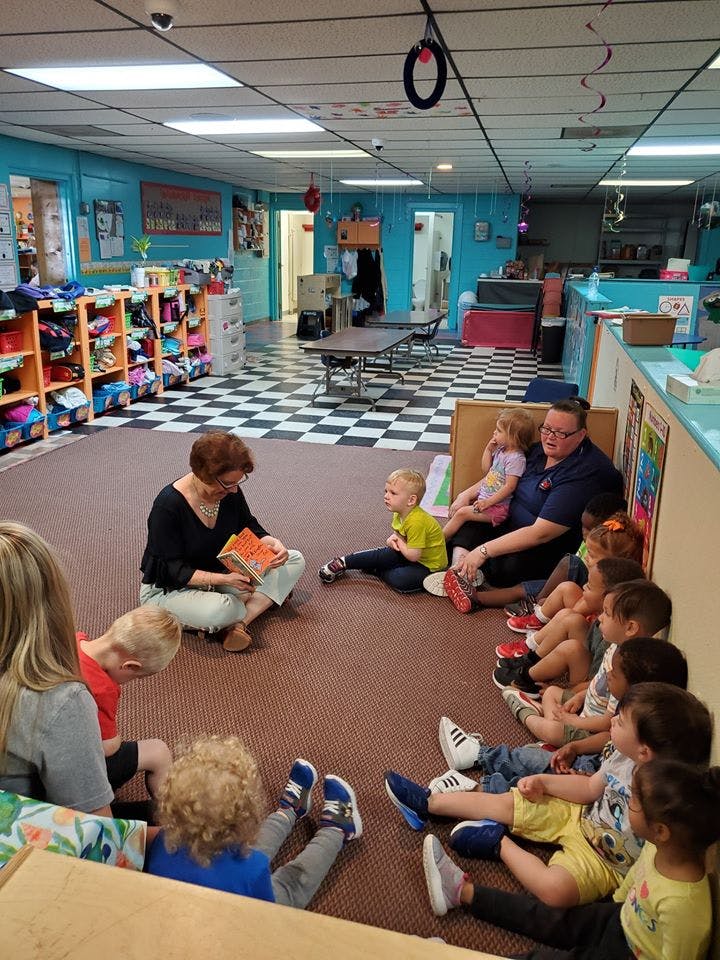 Adults and children sitting on the floor in a classroom