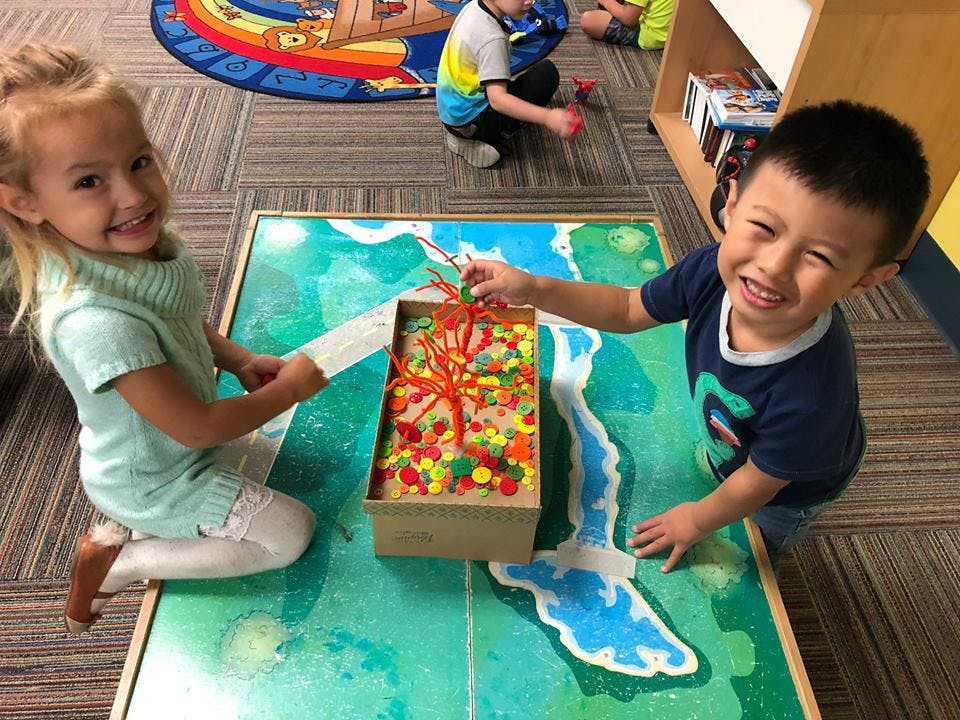 Two children playing with a colorful craft project