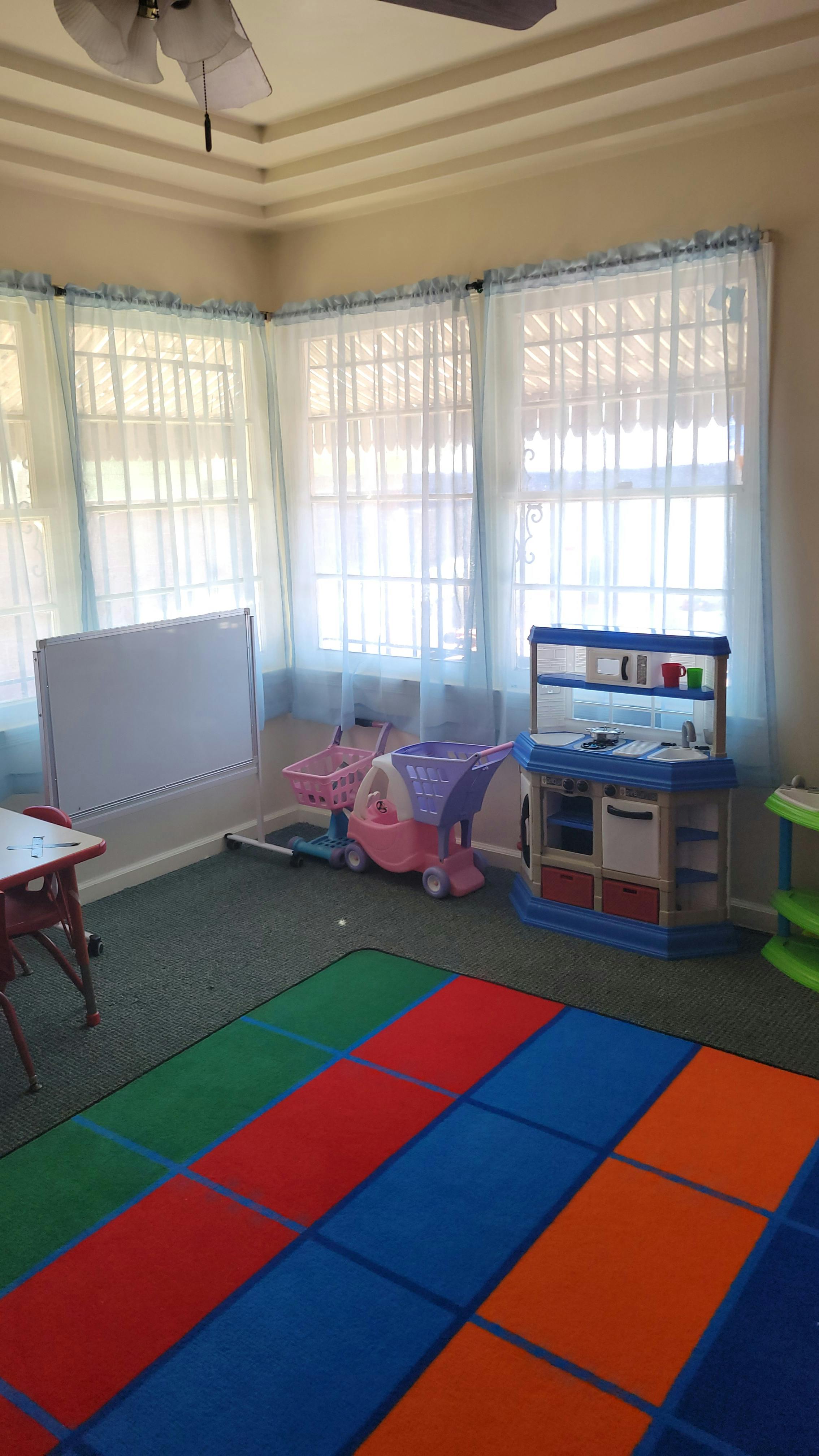 Playroom with toy kitchen, shopping carts, and colorful rug