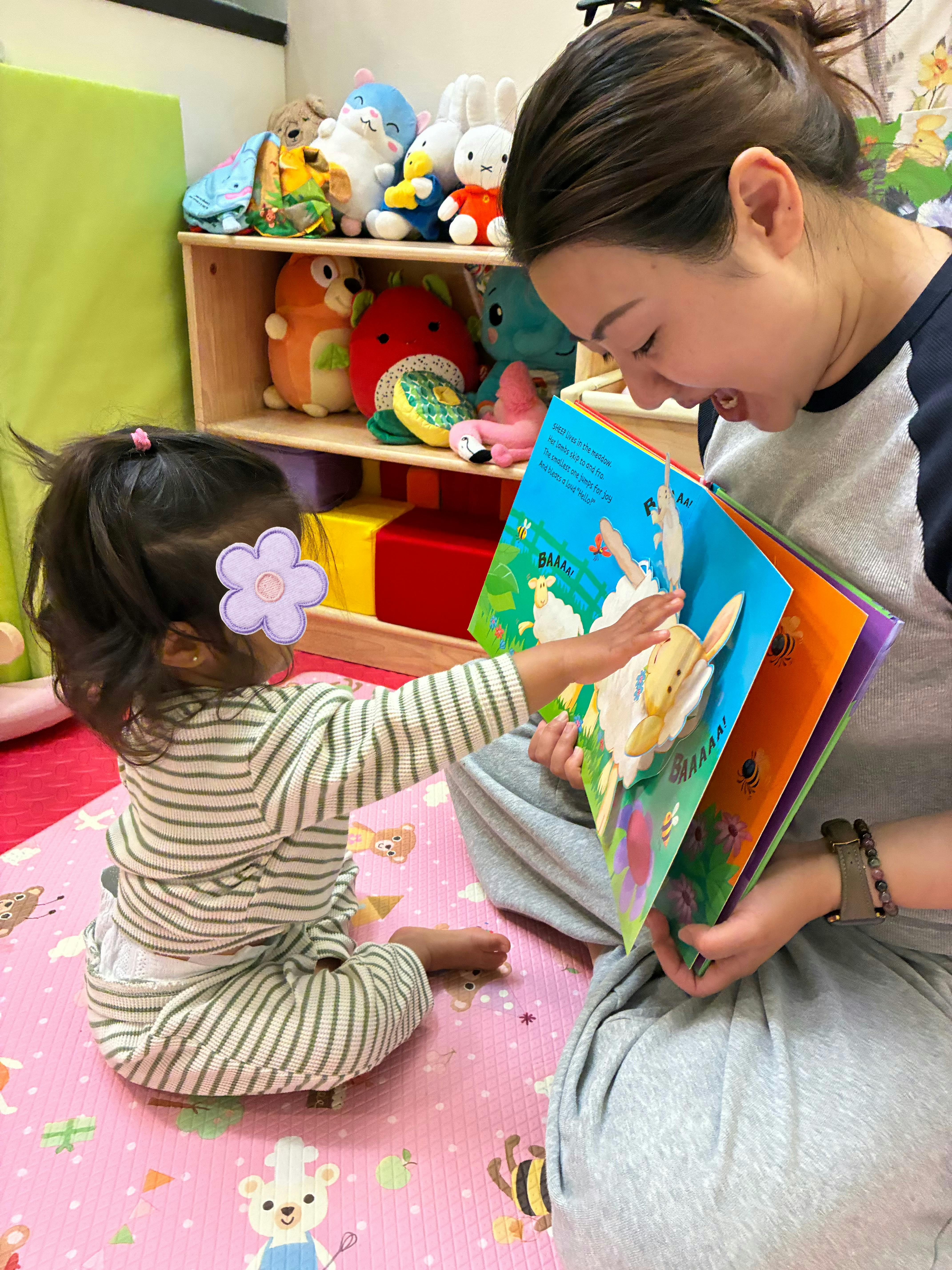 A person reading an interactive book to a child in a playroom