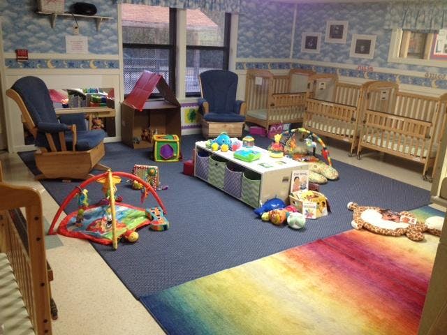 A colorful playroom for infants and toddlers with cribs, playmats, and toys