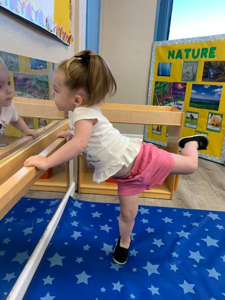 Child looking in a mirror while balancing on one leg