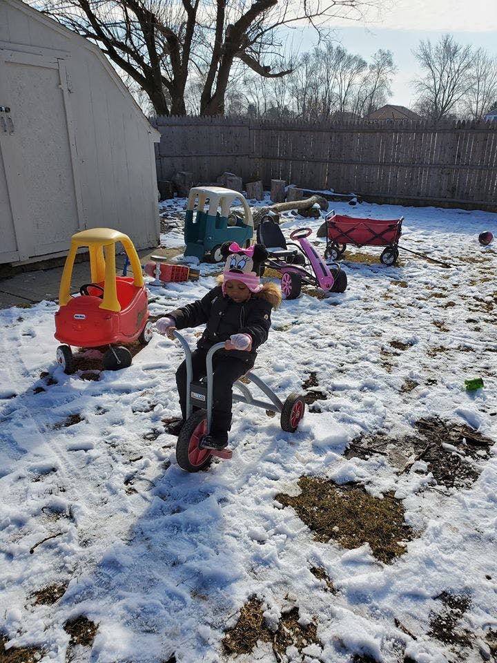 Child on a tricycle in a snowy yard