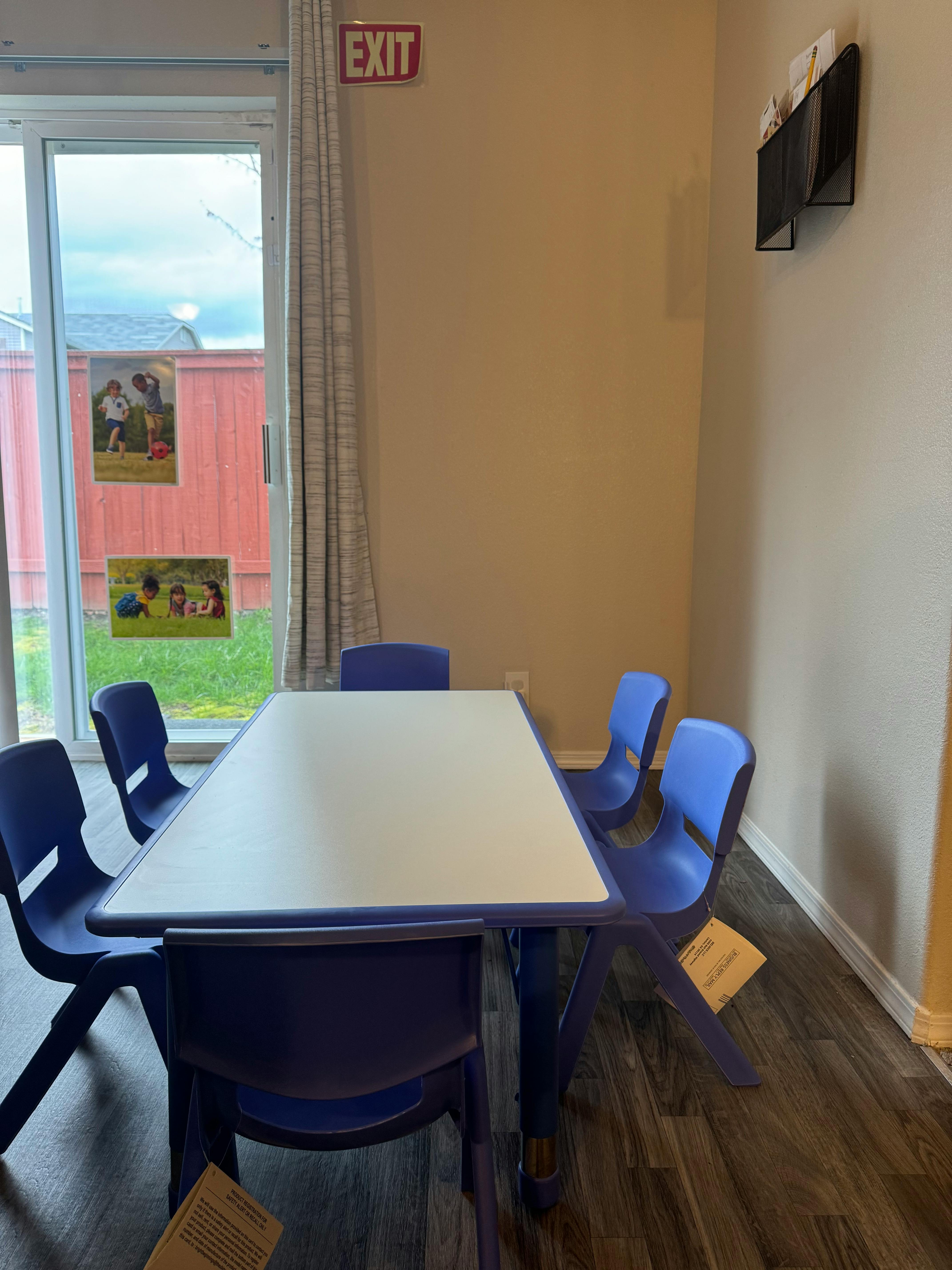 Classroom with a table and chairs, exit sign above a glass door