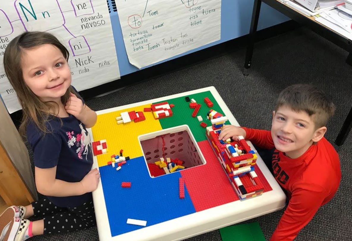Two children playing with building blocks at a table
