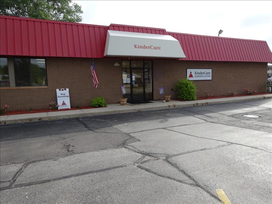 KinderCare Learning Center building exterior with a red roof and "Now Enrolling" sign