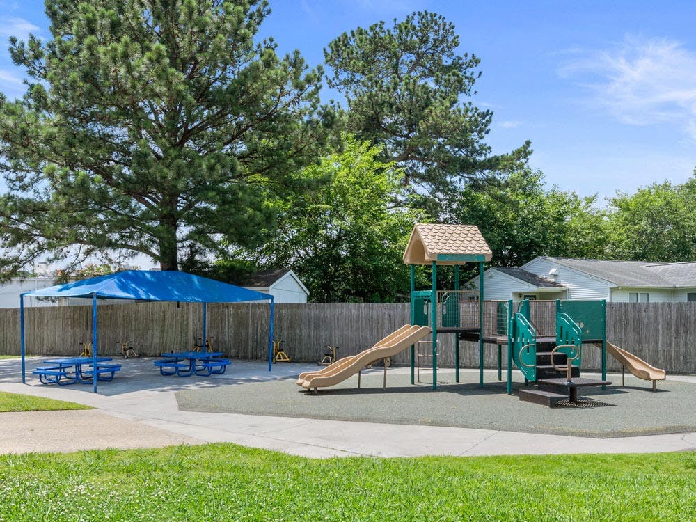 A playground with a climbing structure, slides, and shaded picnic tables
