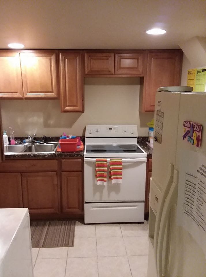 Kitchen with wooden cabinets, white stove, and sink
