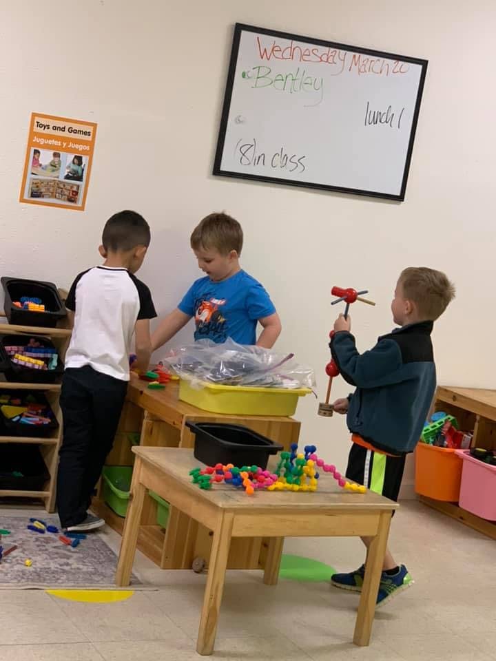 Three children playing with toys in a classroom