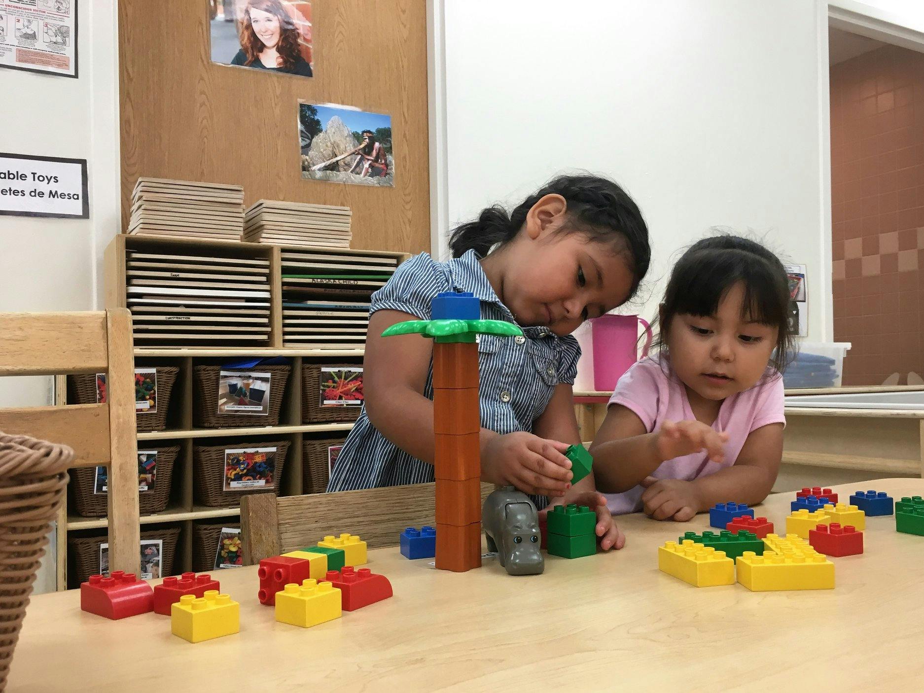 Two children playing with building blocks at a table