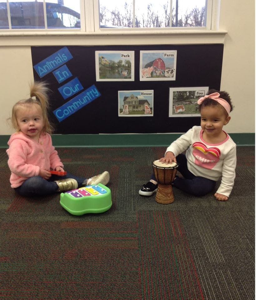 Two children playing with musical toys on the floor