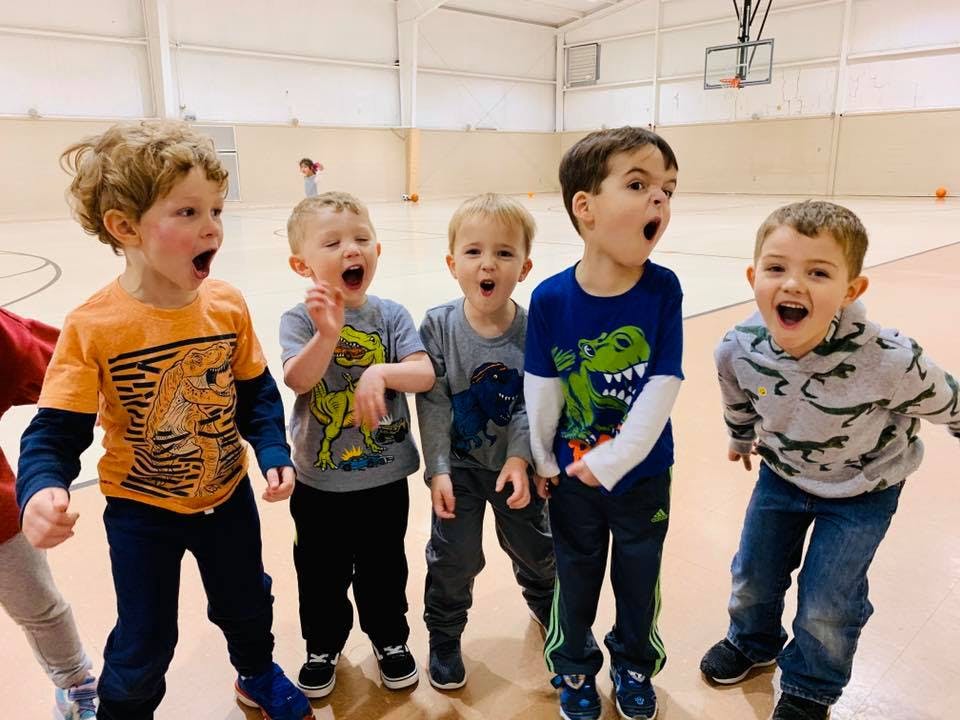 Five children with mouths open in a gymnasium