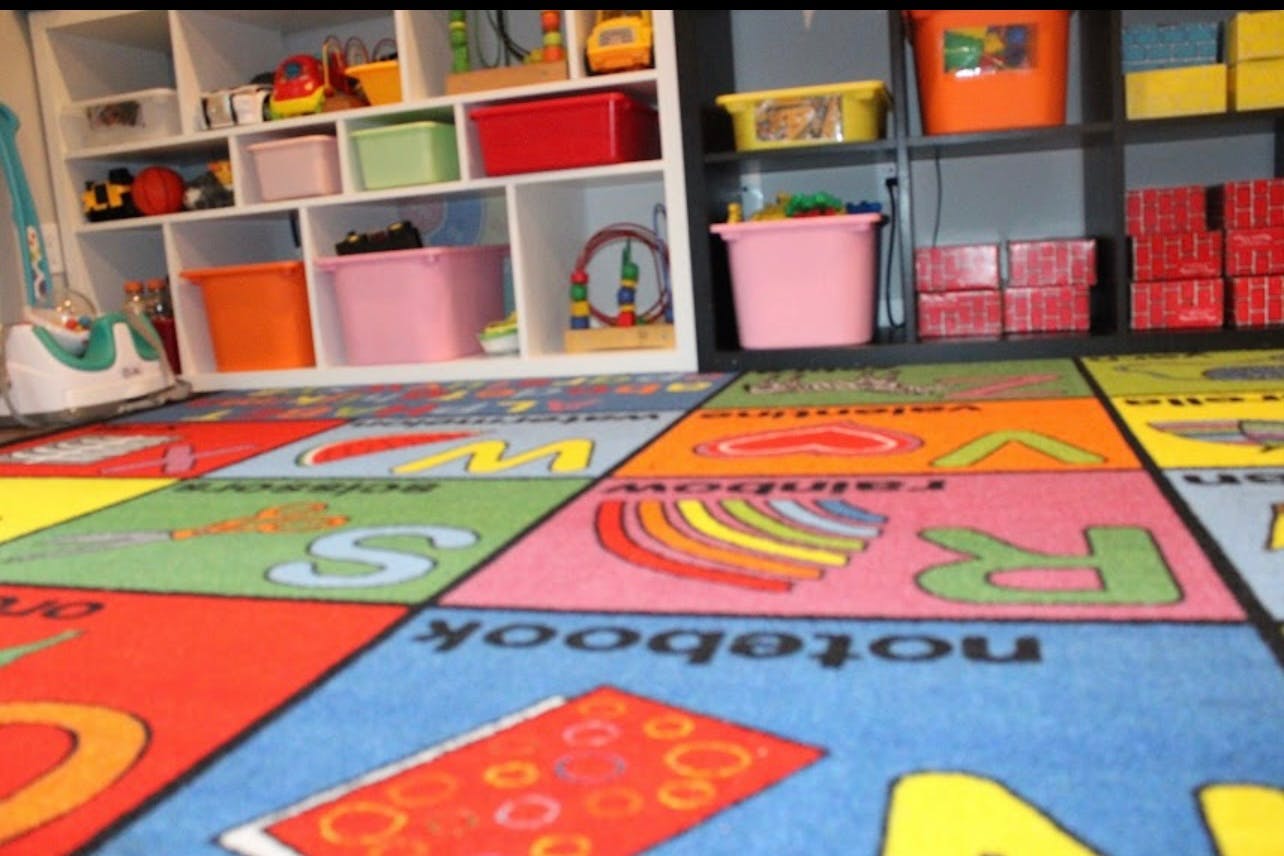 Colorful alphabet rug in a room with shelves of toys and storage bins