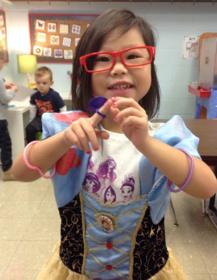 Child in red glasses and costume holding a small object