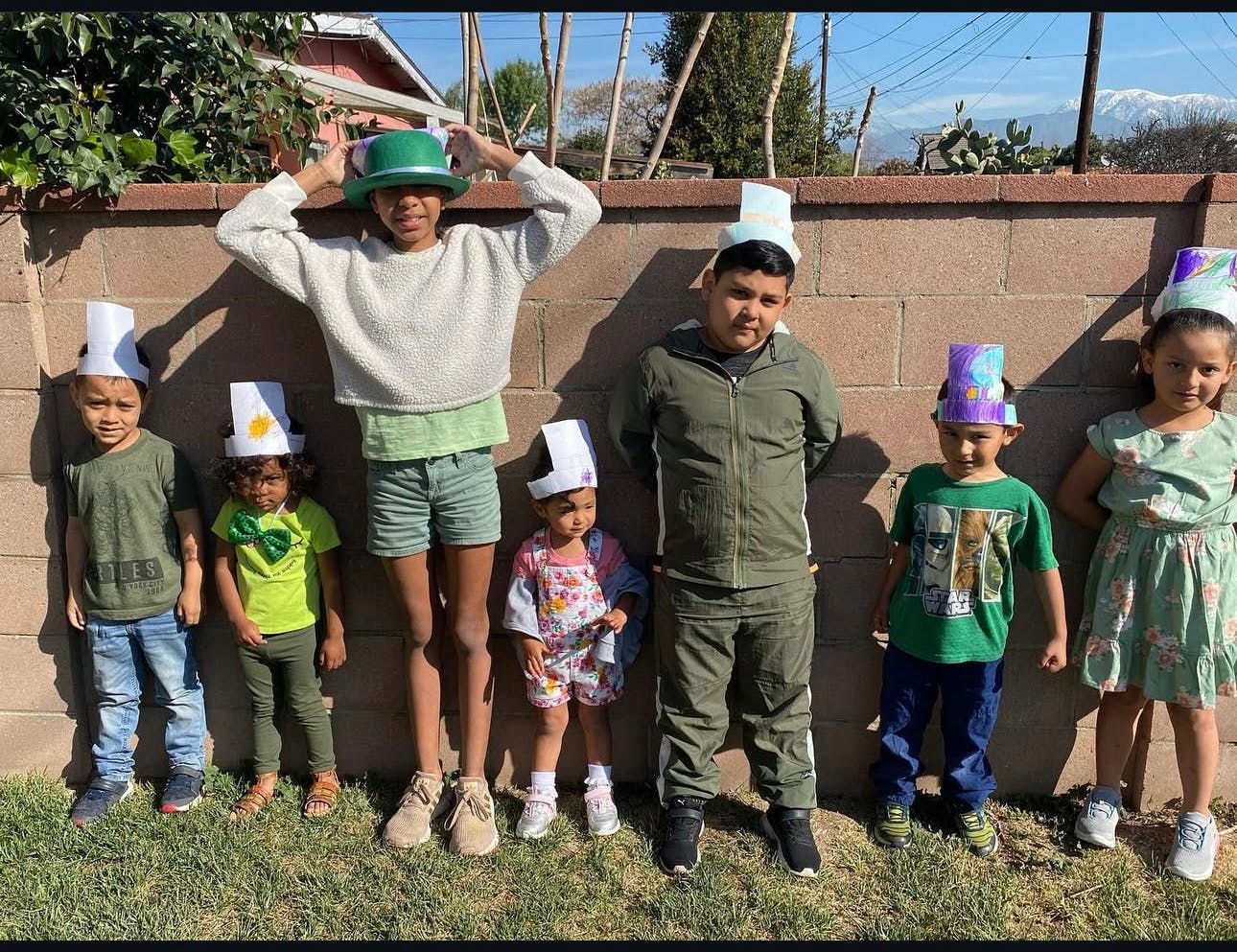 Group of children and teens wearing hats standing in front of a wall