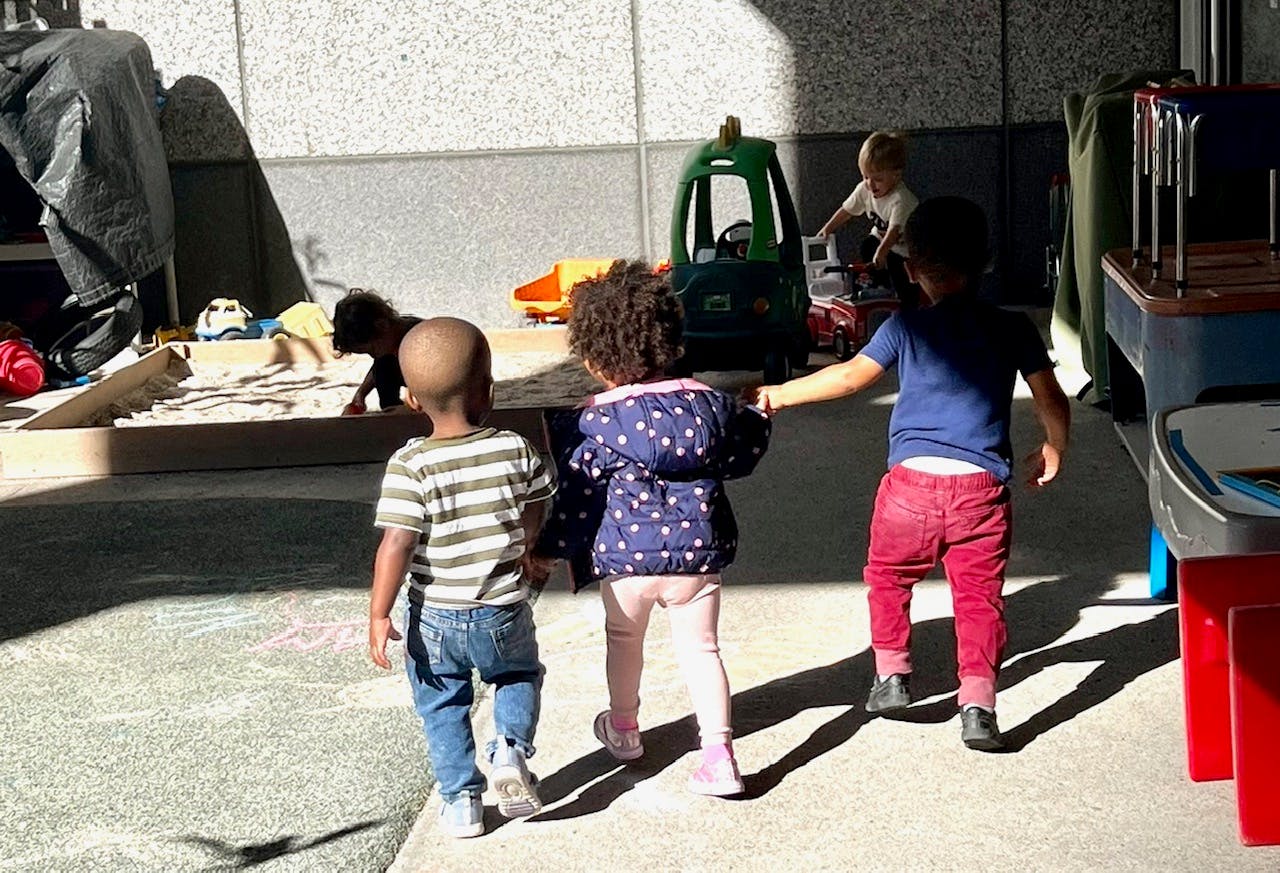 Three children walking together, one holding another's hand