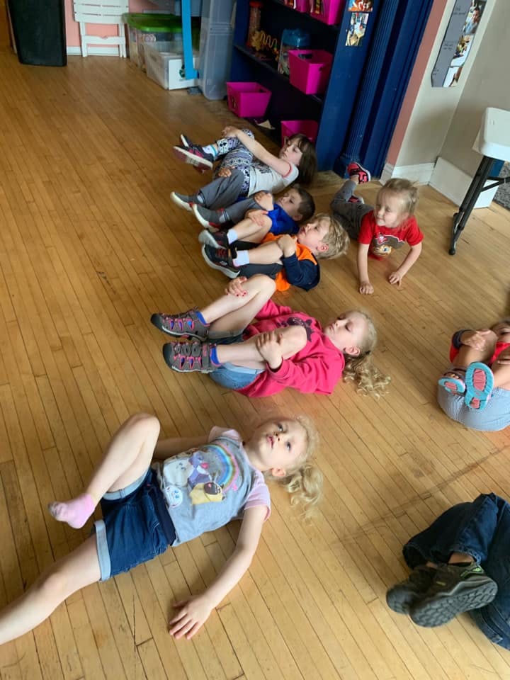 Multiple children lying on a wooden floor