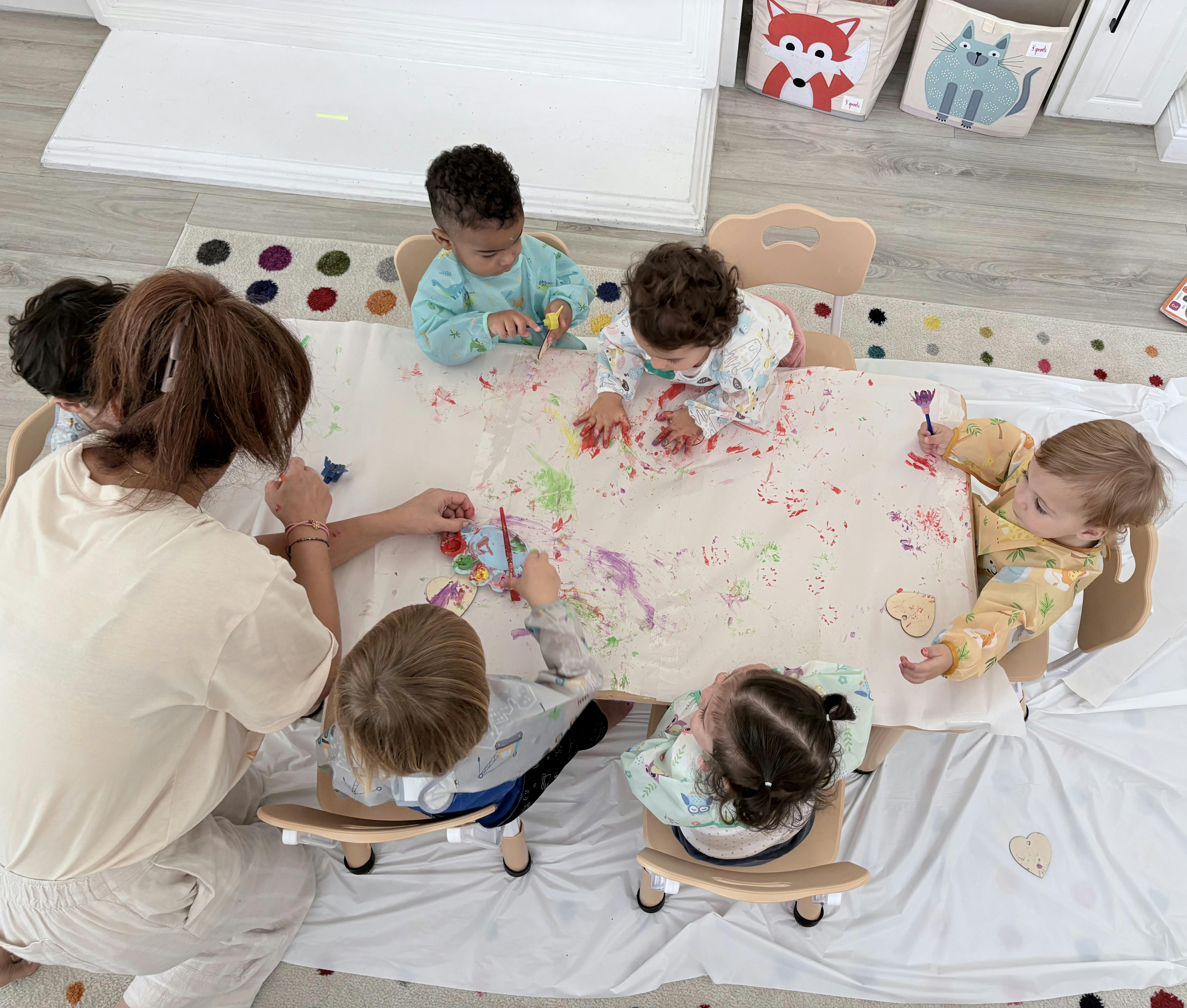 Adult and group of children painting at a table