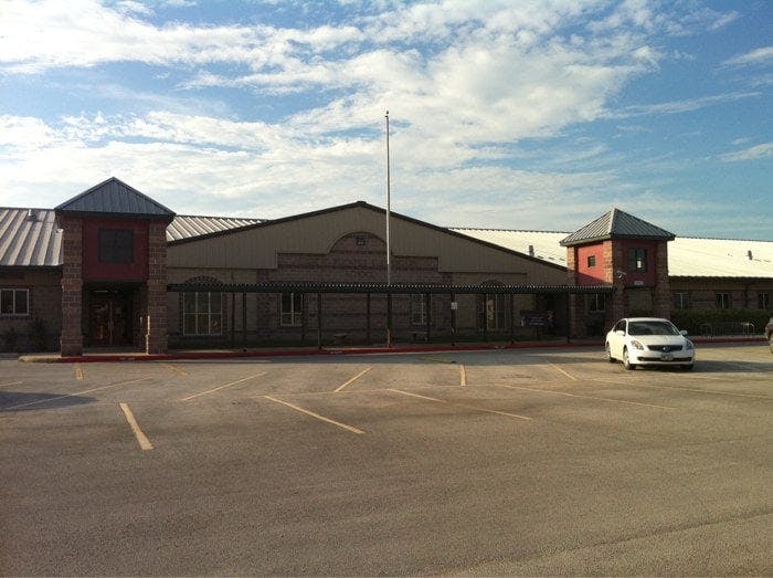 Building with a parking lot in front and a white car