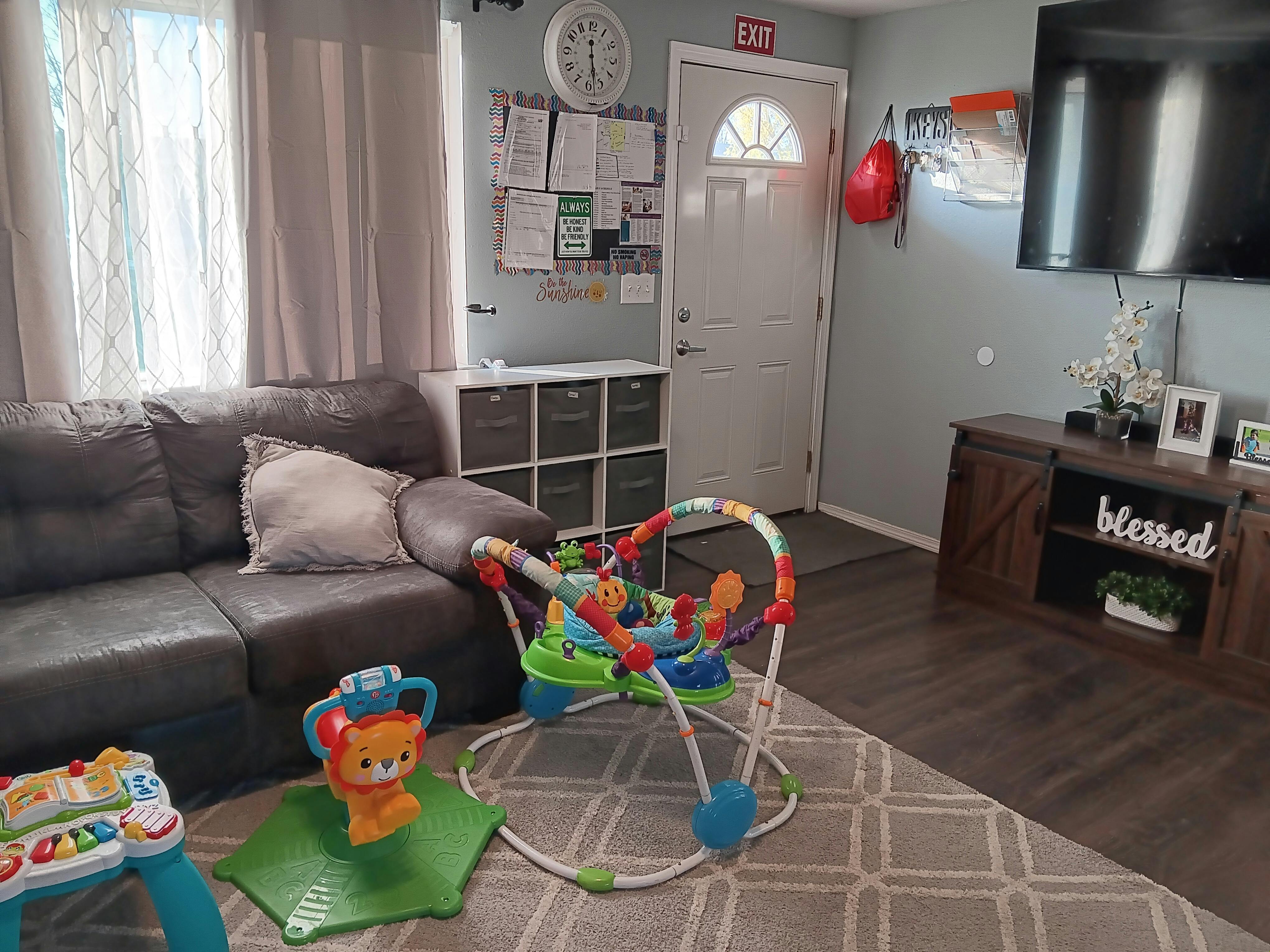 Living room with a gray couch, baby bouncer, and entertainment center