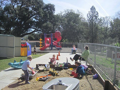 Children playing in a sandbox and on playground equipment