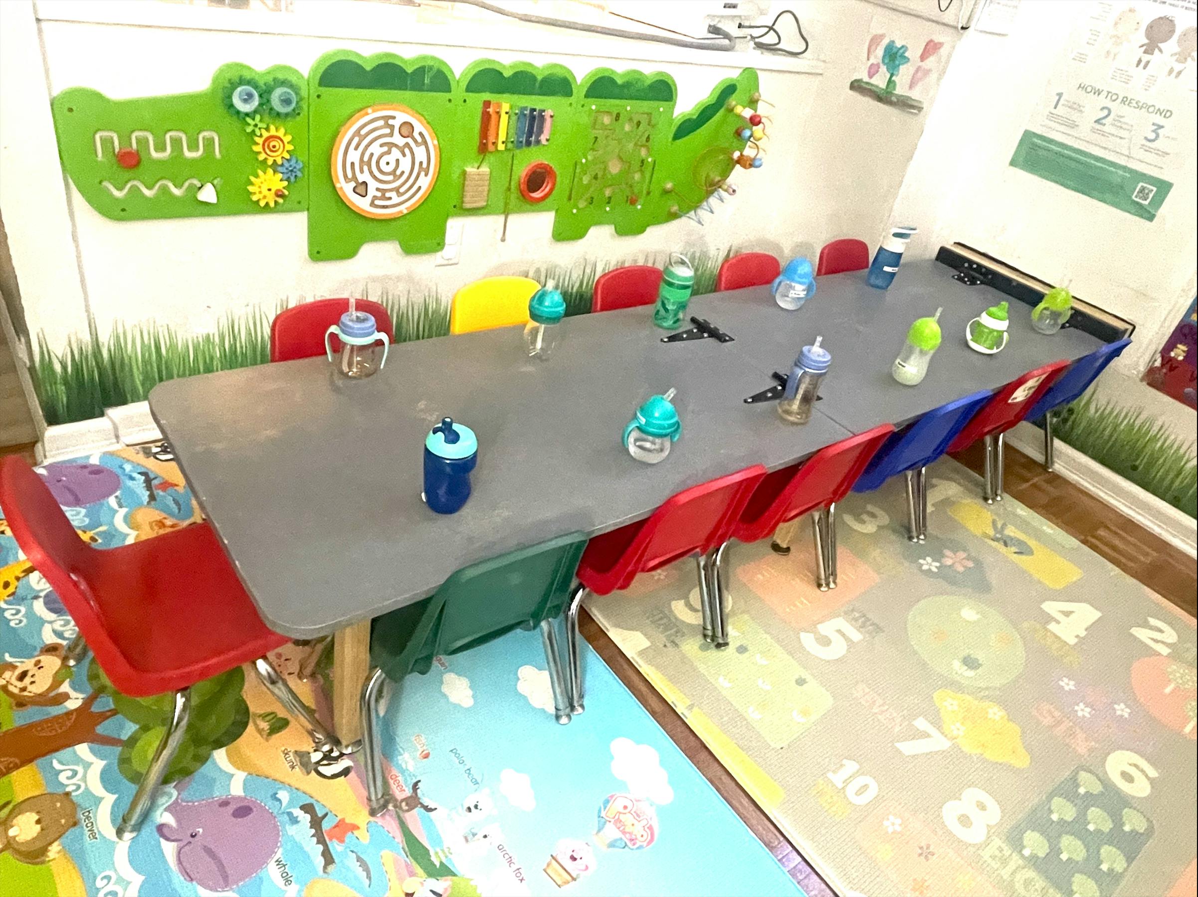 Classroom with a long table and chairs, sippy cups on the table
