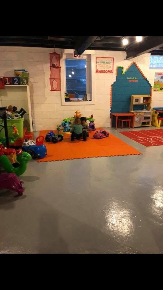 Two children playing with toys on an orange mat in a playroom