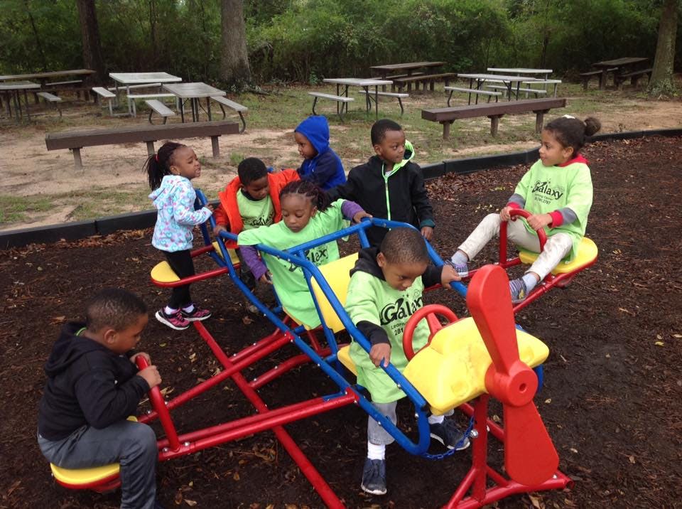Children playing on a seesaw and other playground equipment