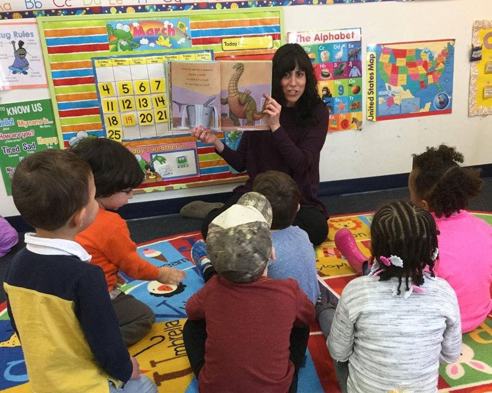 Person reading a book to children in a classroom