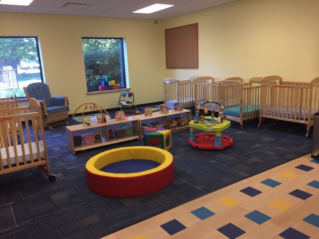 Nursery room with multiple cribs, a playpen, and a small table with toys