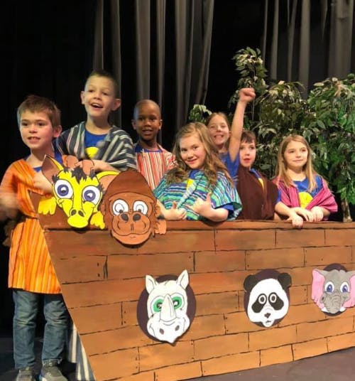 Children in costumes on a stage with animal cutouts