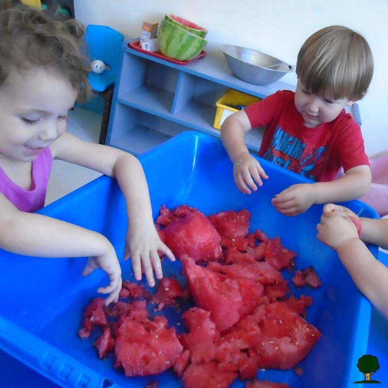 Children playing with red material in a blue bin