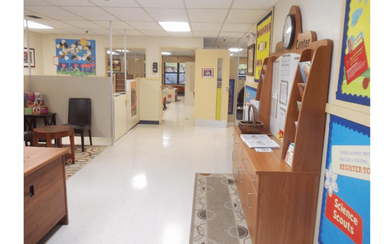 An empty daycare or school hallway with bulletin boards and furniture