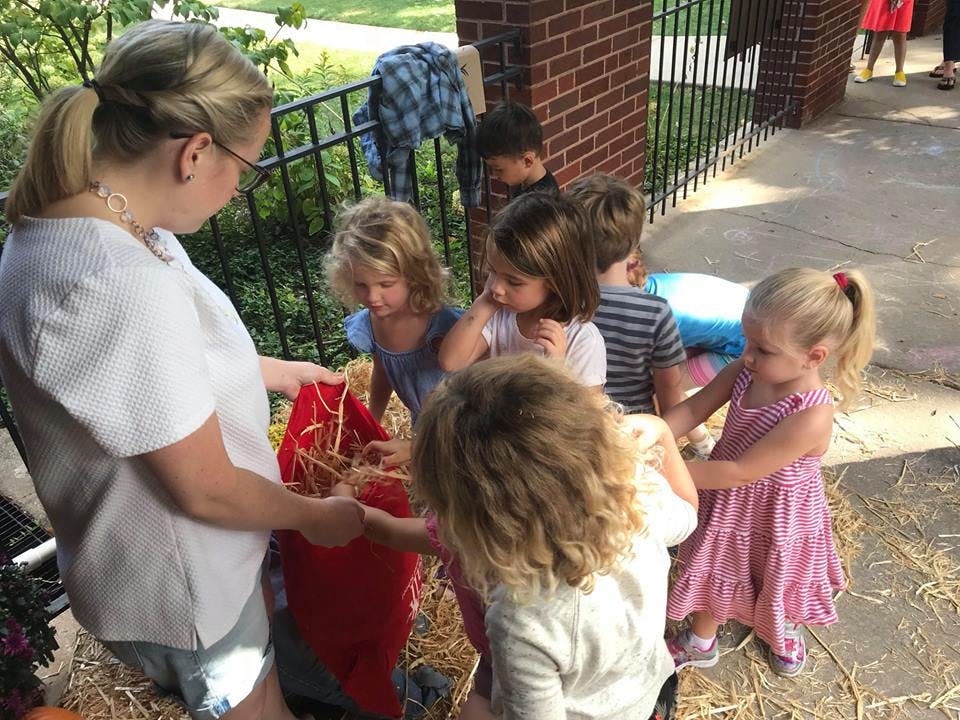 Person and children interacting with a scarecrow