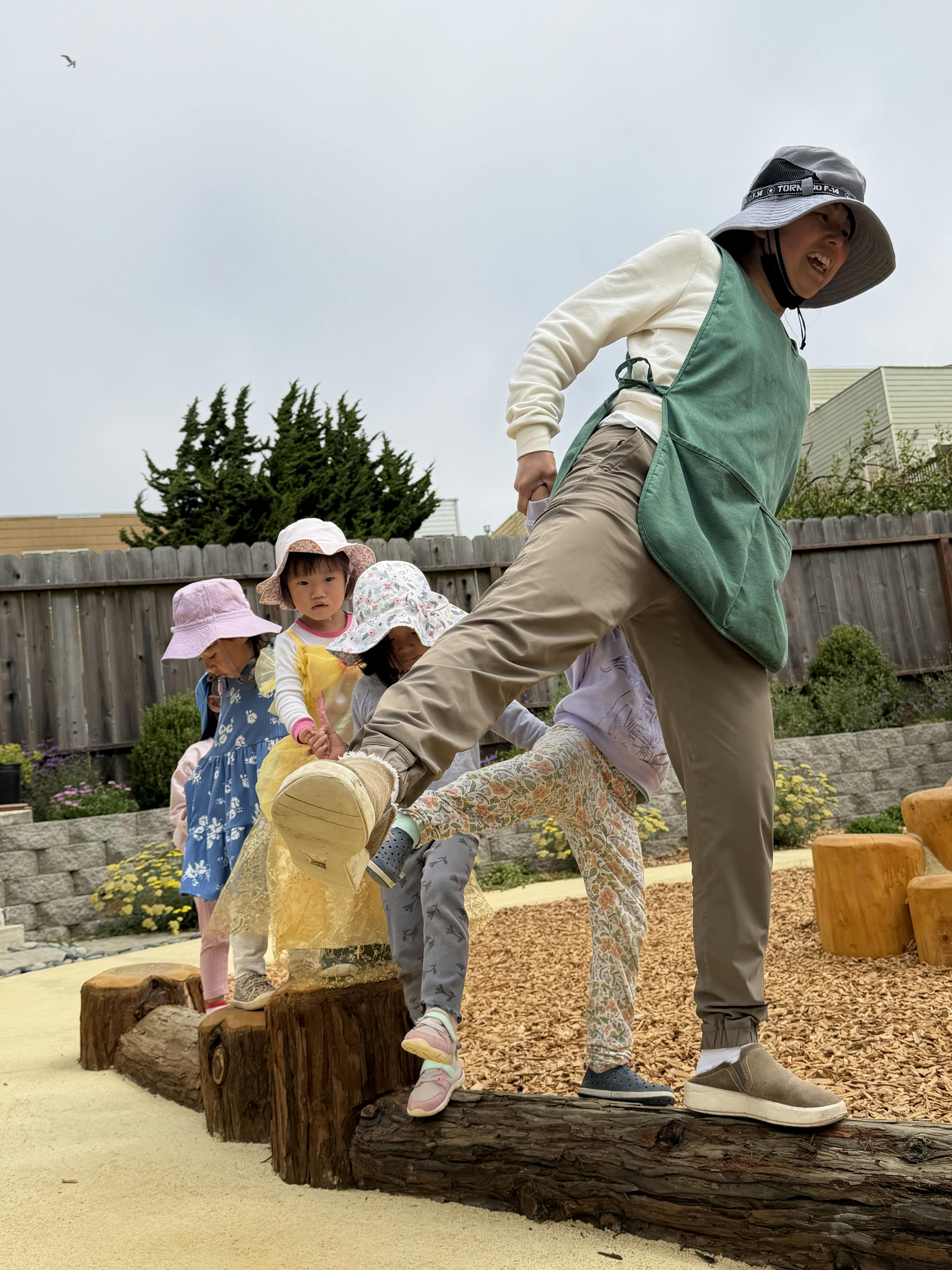 A person and children balancing on a wooden beam on a playground