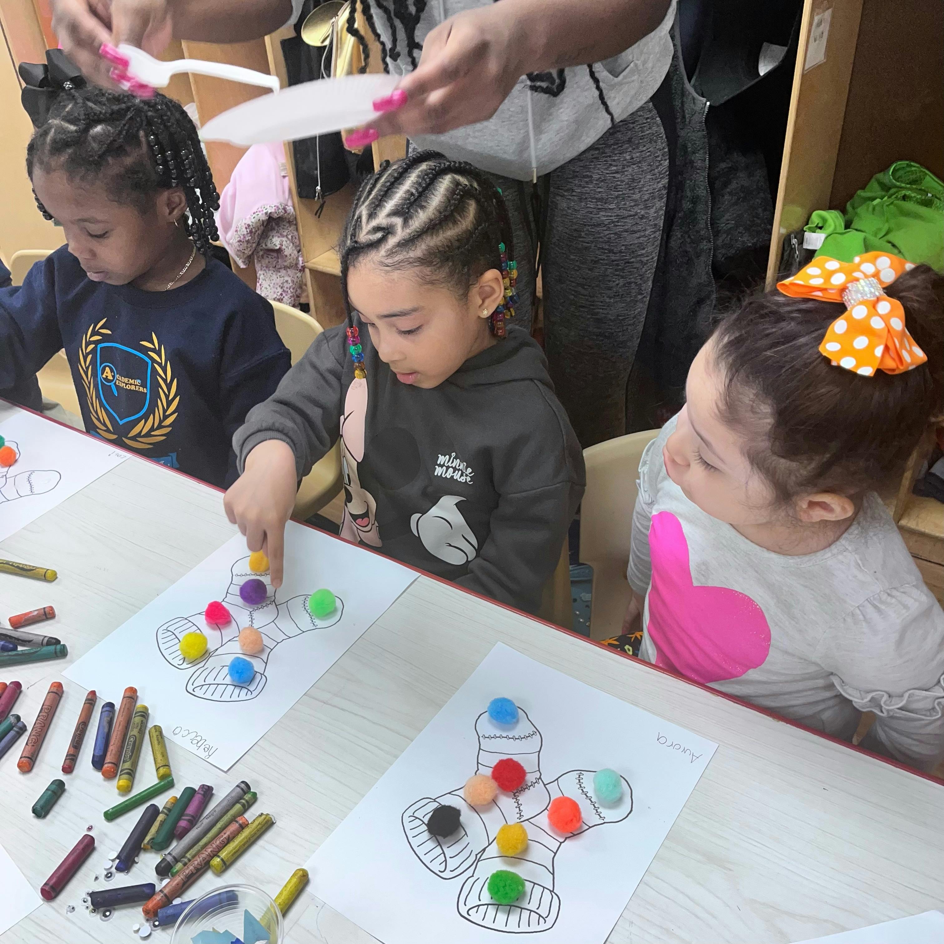 Children doing an art activity with pom-poms and crayons