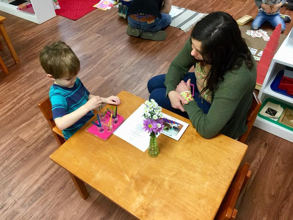 Child and person at a table with a toy and flowers