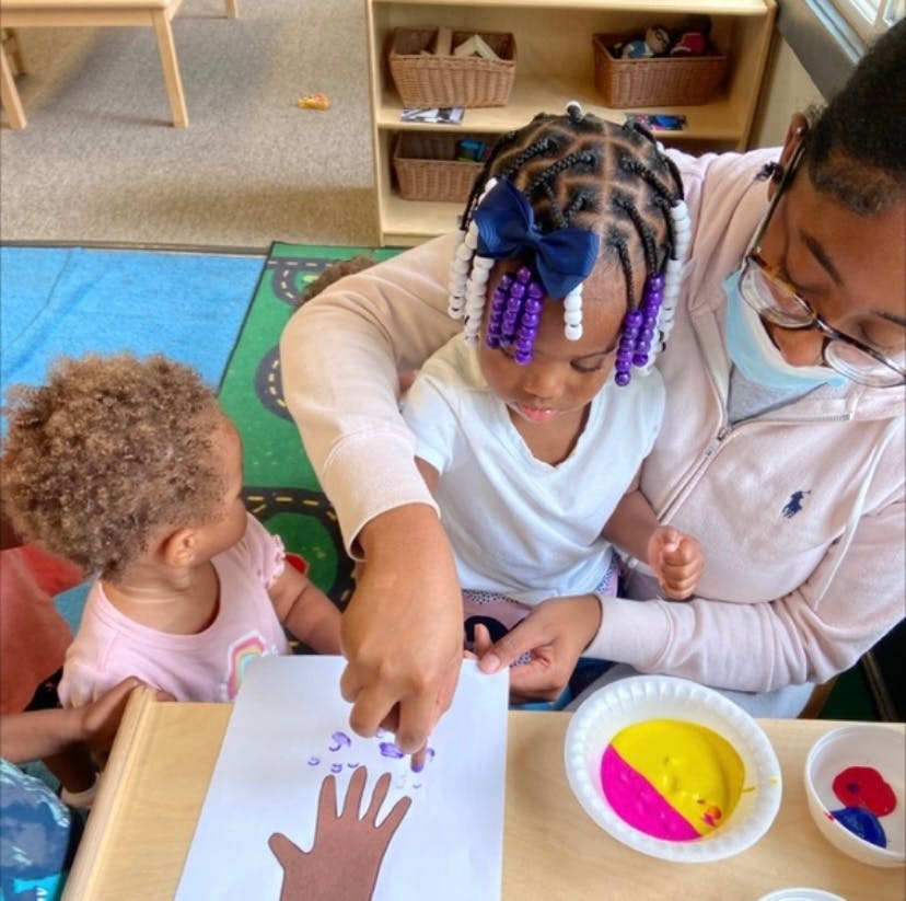 Adult and two children doing a handprint craft with paint