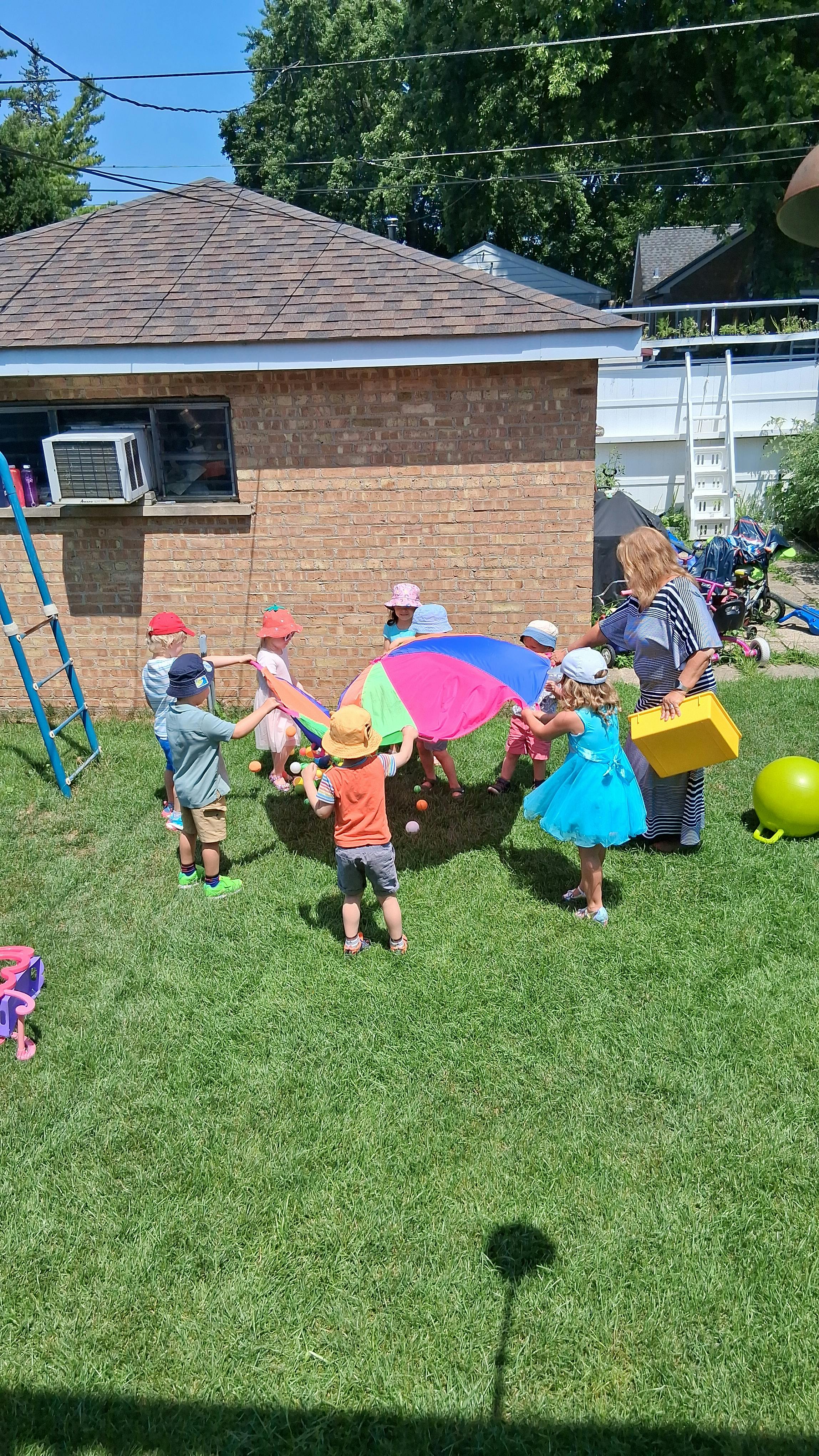 Adult and children playing with a colorful parachute on grass