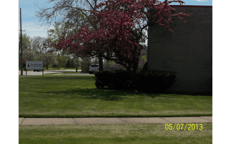 Sign for KinderCare Learning Center on a grassy lawn with a flowering tree
